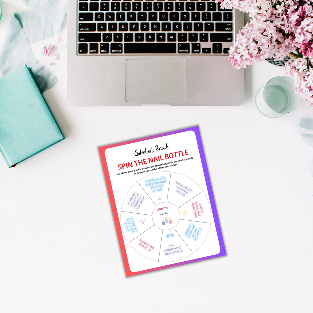 A laptop and flowers sit beside a printed "Galentines Brunch Invitation & Party Games PLR" game sheet on a white table, creating the perfect ambiance for a delightful Galentines brunch filled with laughter and fun activities.