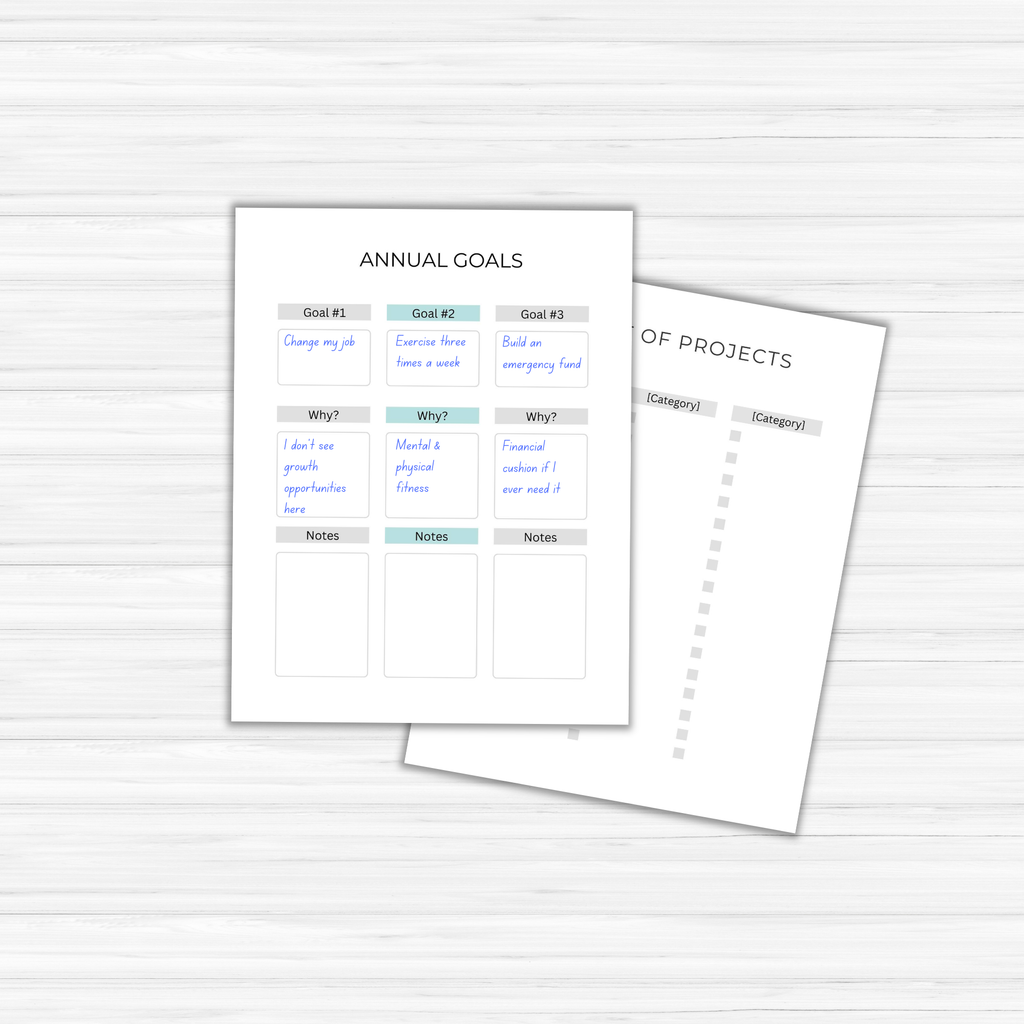 Two paper templates rest on a wooden surface; The Goal-Setting Planner outlines annual objectives and reasons, while the other is a project list with blank categories ready to be filled.