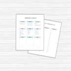 Two paper templates rest on a wooden surface; The Goal-Setting Planner outlines annual objectives and reasons, while the other is a project list with blank categories ready to be filled.