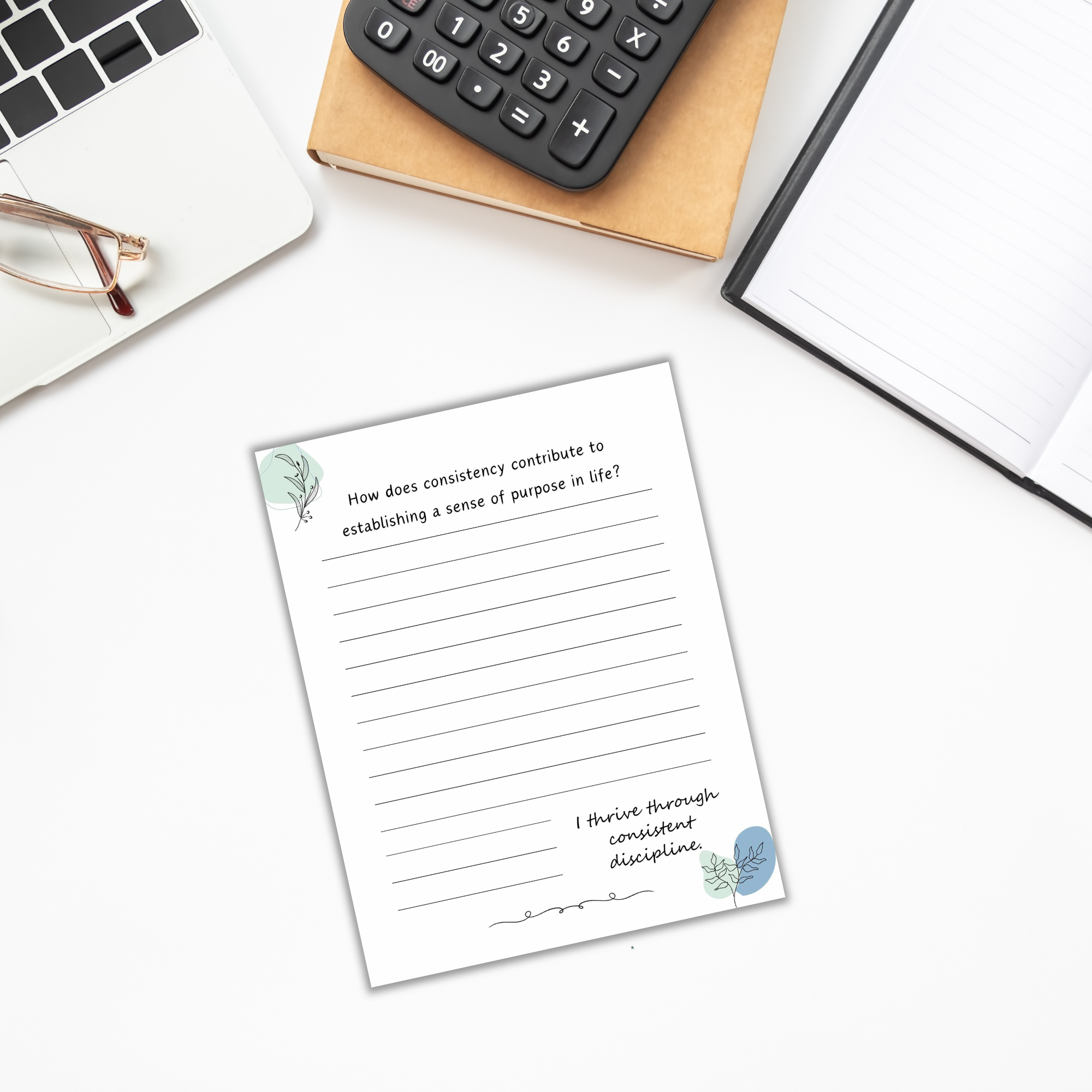 Flat lay of "The Power of Momentum Journal & Workbook" open to a question about consistency, with a calculator, glasses, and notebook strategically arranged on the white surface.