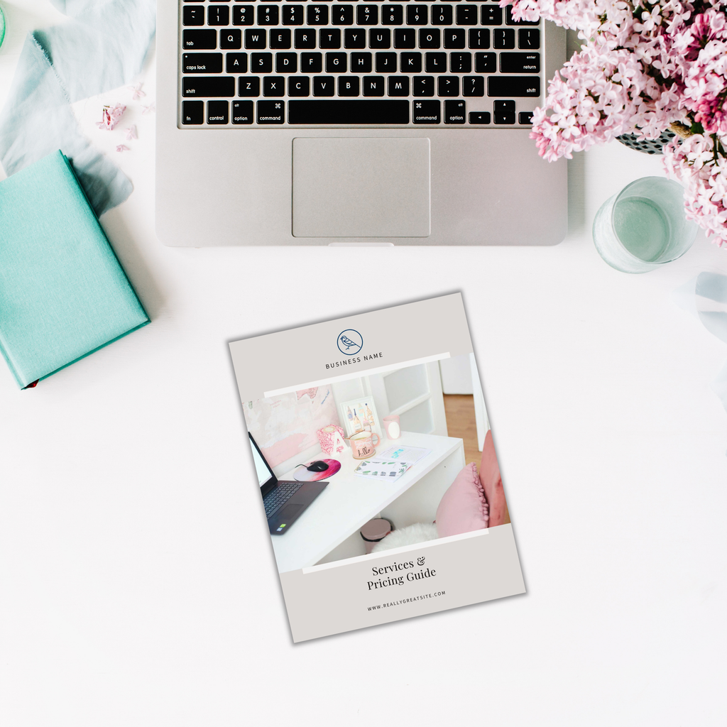 Open laptop on a table with a teal book, the Services and Pricing Guide featuring a floral cover, a candle, and pink flowers nearby.