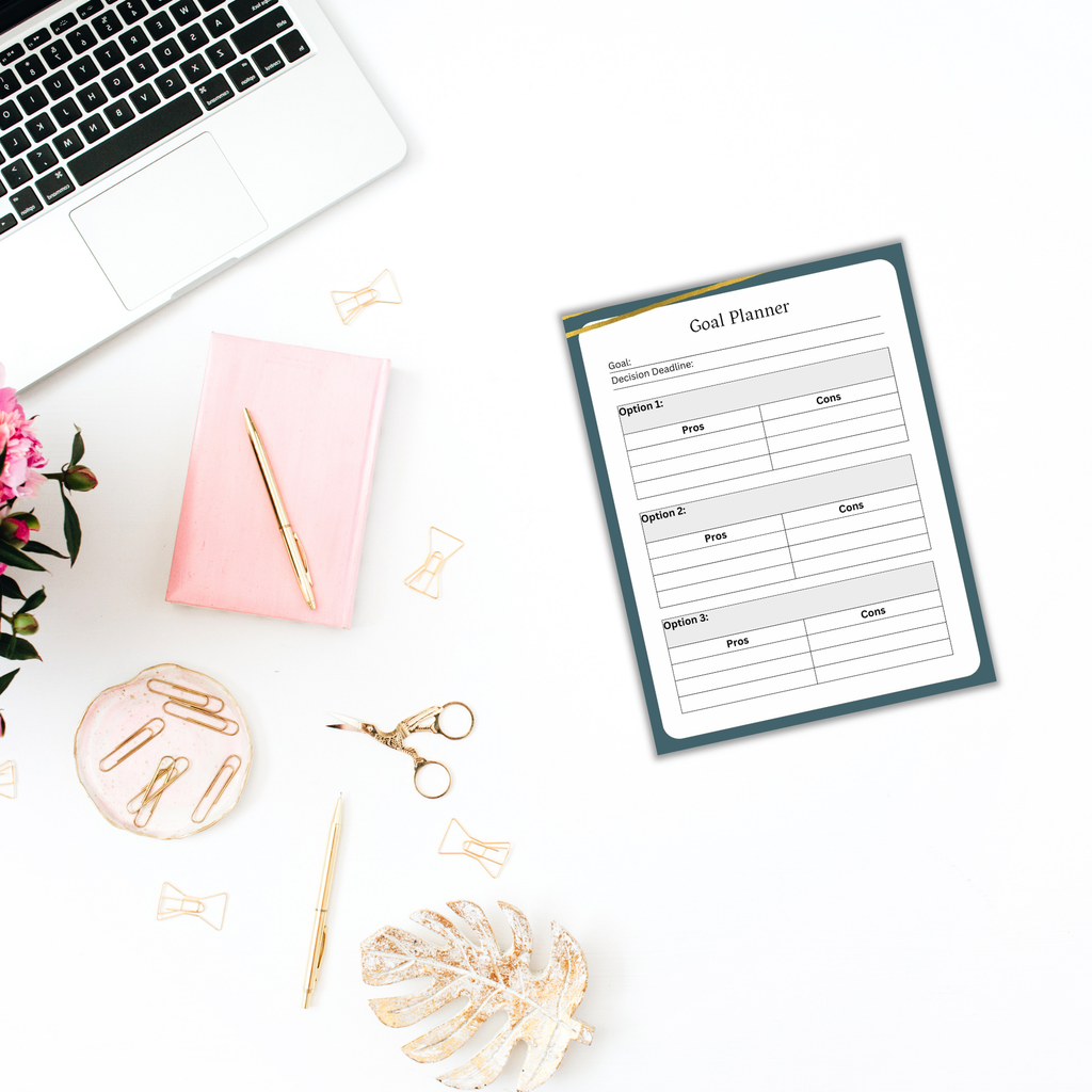 A solopreneur's goal planner sits on the desk alongside a laptop, pink notebook, pen, and The Solopreneur Success Pack, which includes decorative items like flowers, paper clips, scissors, and a leaf—creating an inspiring workspace.