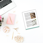 A flat lay featuring a laptop, the Summer Pastels Ebook Templates, a pink notebook, a pen, a magazine page, and various gold stationery items on a white surface beautifully captures the essence of creative workspaces. The scene's summer pastels are complemented by the greenery of the plant.
